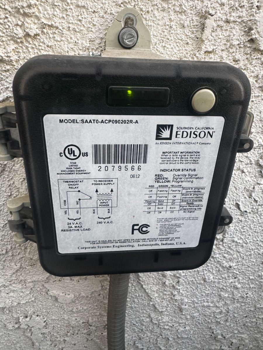 Southern California Edison smart meter with green indicator light mounted on concrete wall